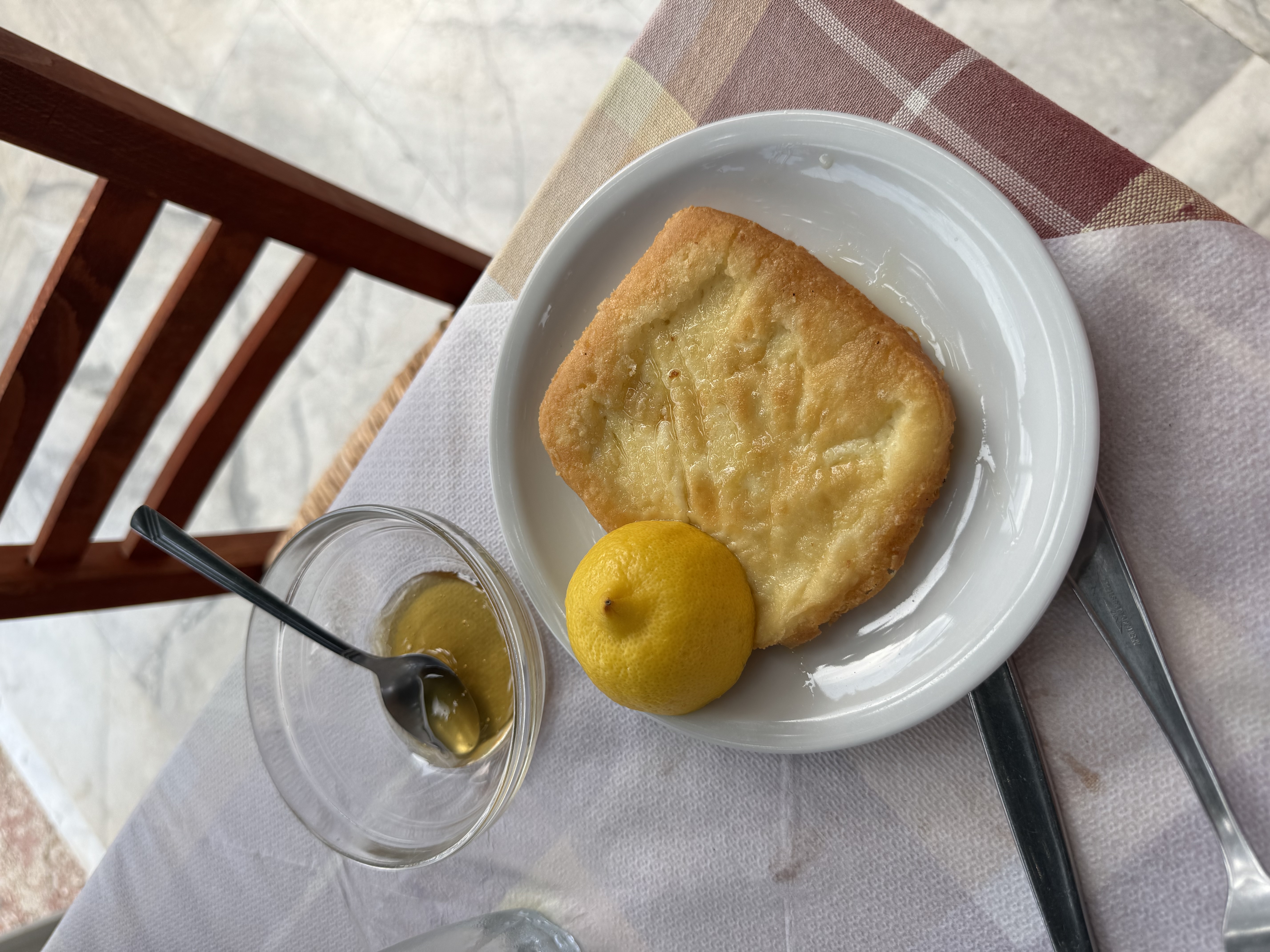 A Greek taverna table with golden fried cheese, lemon and olive oil