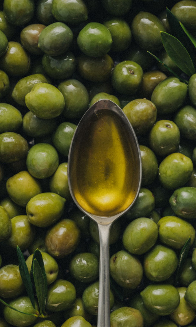 Olive oil on a spoon among green olives