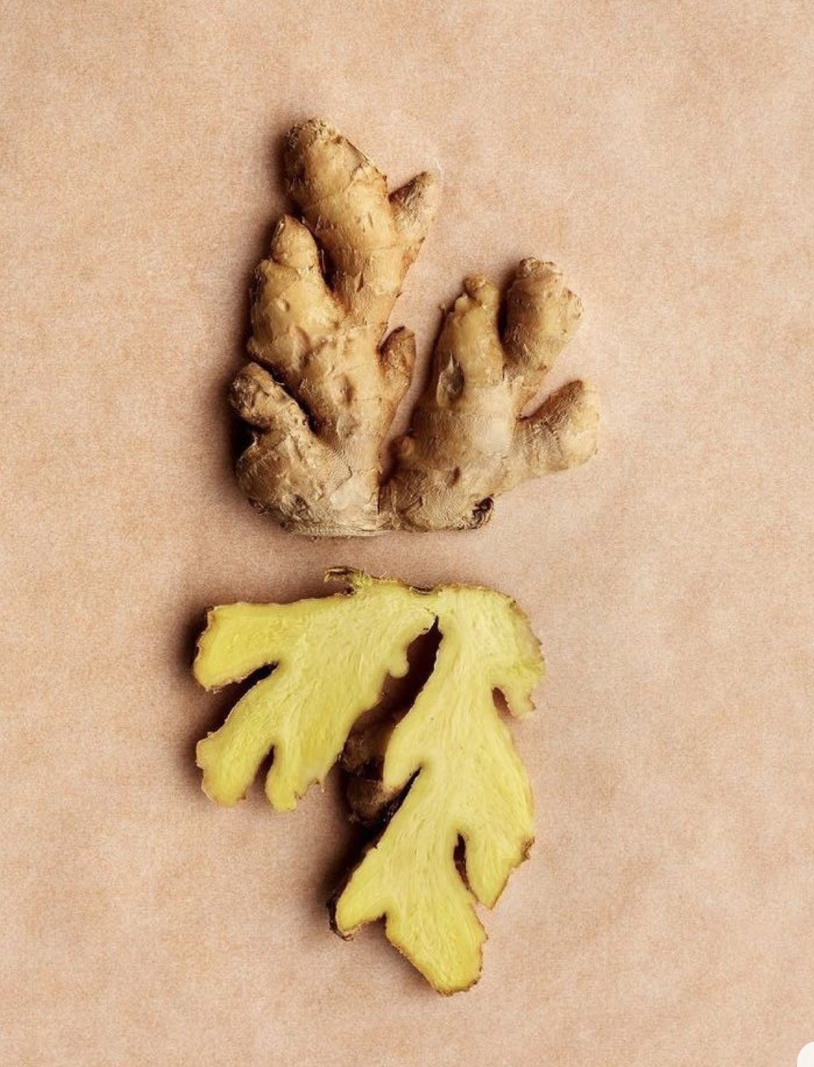 Fresh ginger root and sliced ginger on a pale background