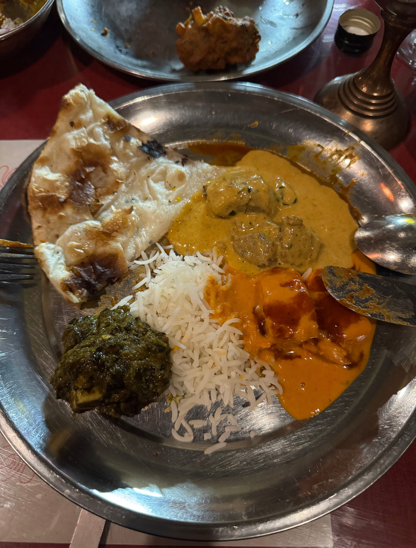 A Montréal meal with rice, curries and naan served on a metal plate